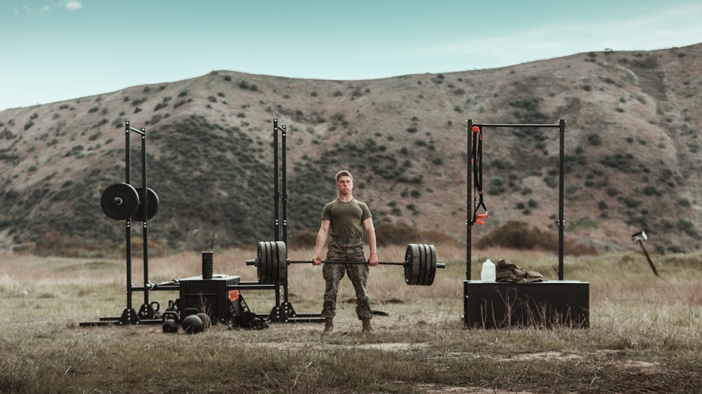 man in gray tank top and black pants standing on brown field during daytime