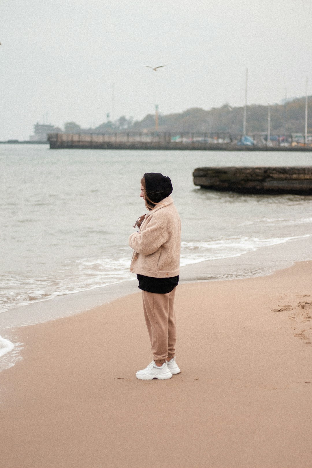 woman in pink hoodie standing on beach during daytime