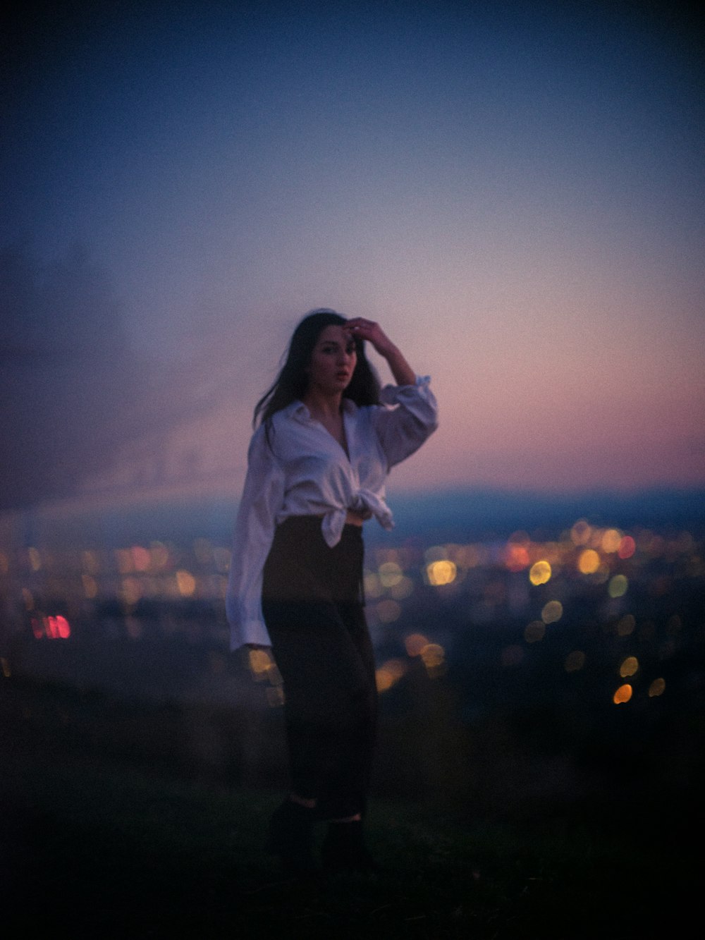 woman in white long sleeve shirt and black pants standing on road during daytime