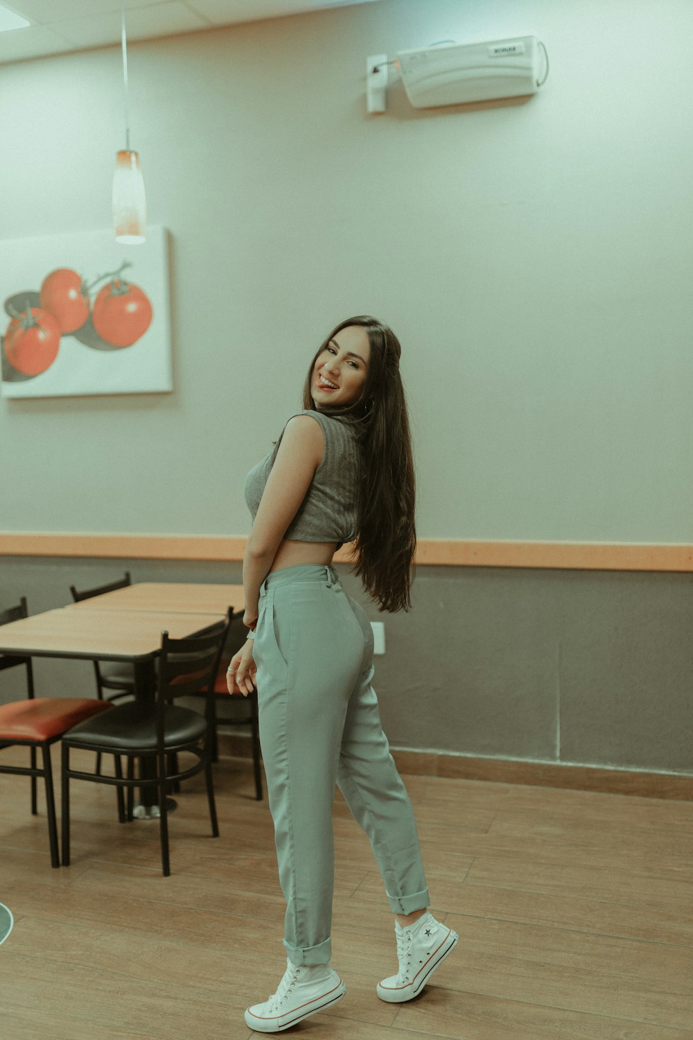 woman in gray tank top and blue denim jeans standing near table