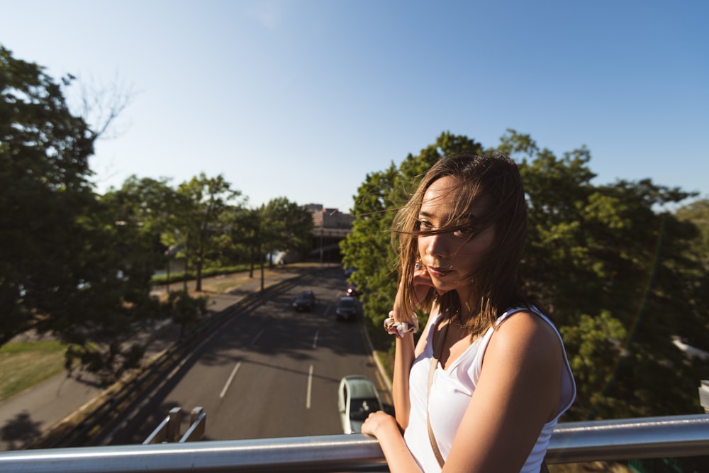 woman in white tank top sitting on car hood during daytime