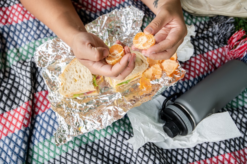 person holding brown bread with orange on top