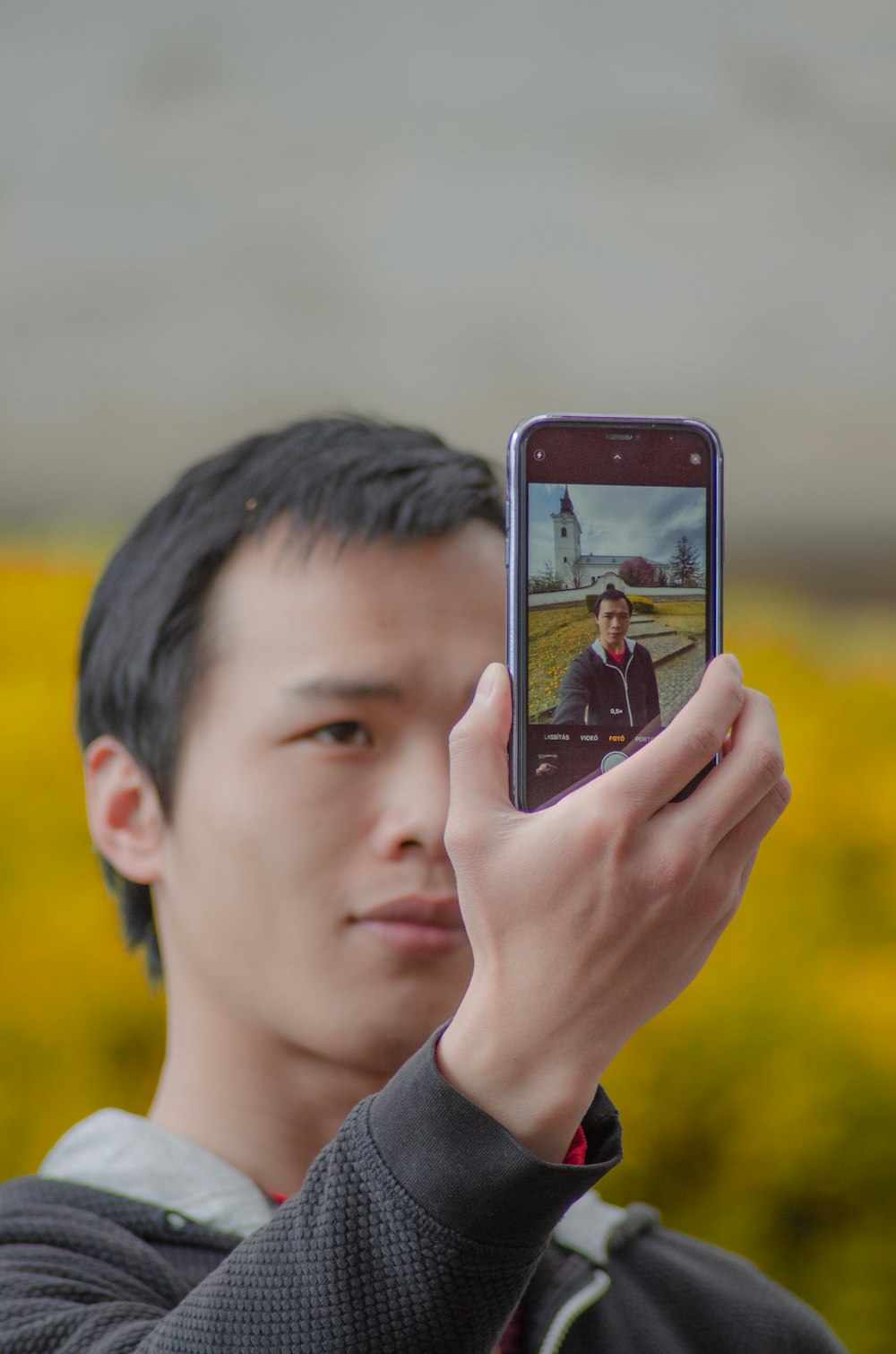 man in gray shirt holding black smartphone