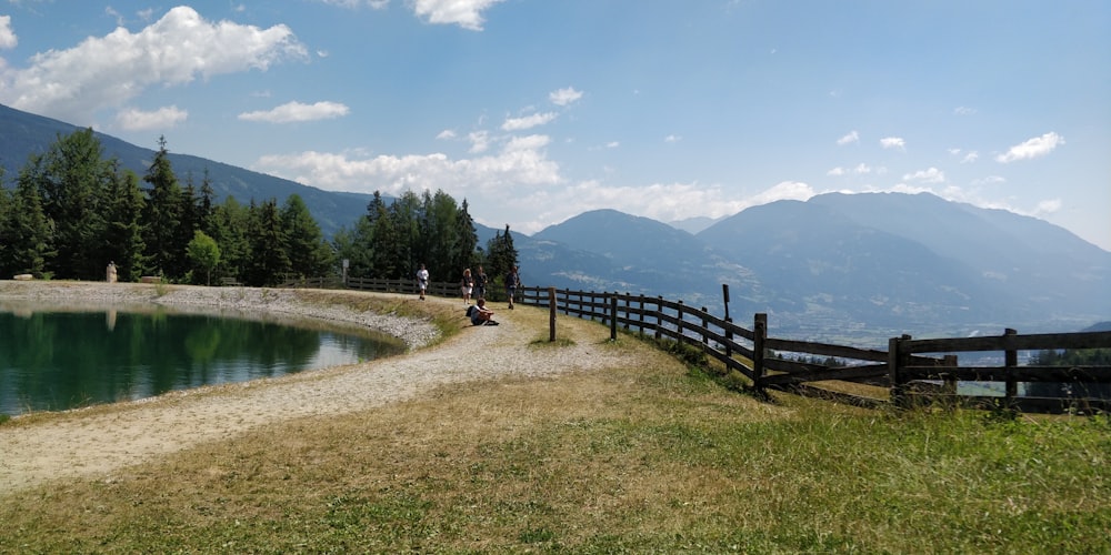 people walking on brown wooden fence near lake during daytime