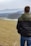 man in black jacket and blue denim jeans standing on green grass field during daytime
