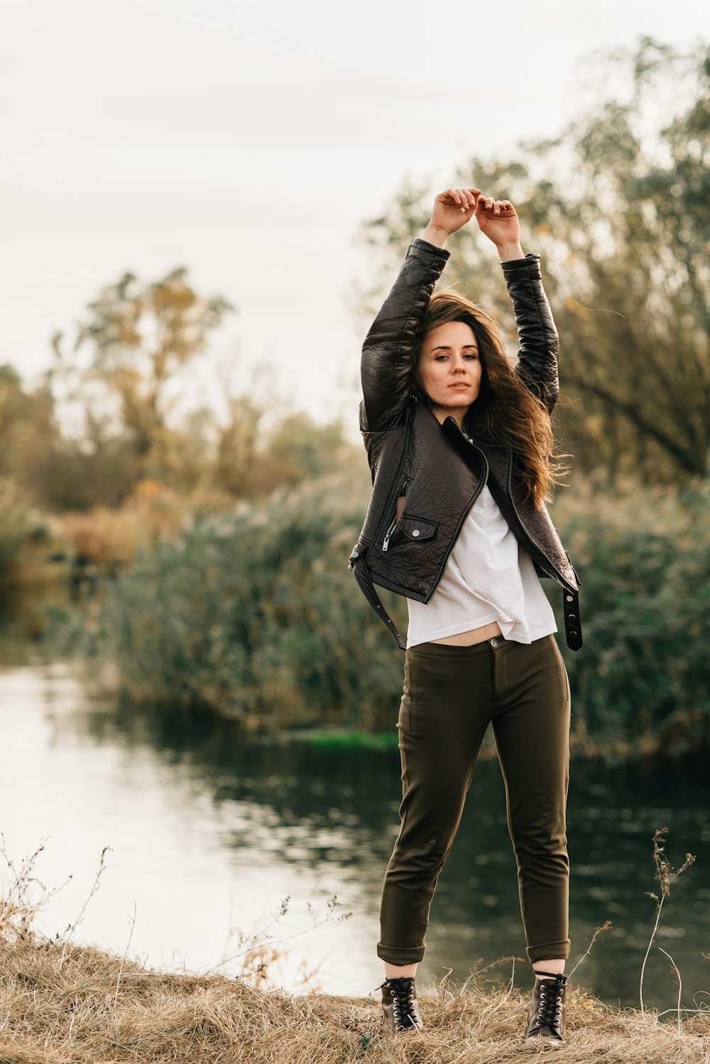 woman in black jacket standing near lake during daytime