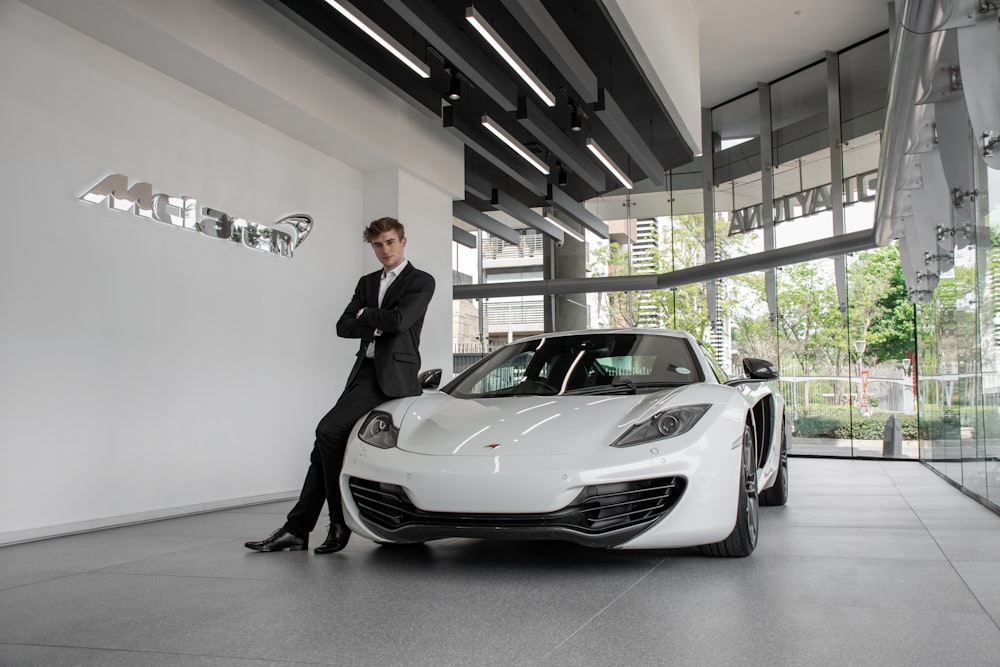 man in black suit standing beside white porsche 911