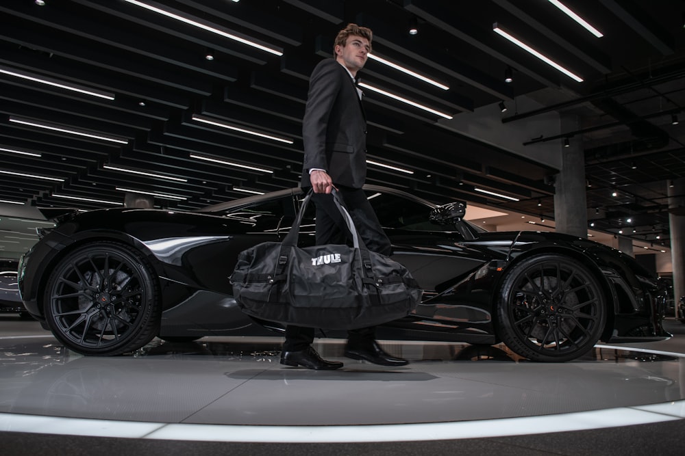 man in black suit standing beside black car