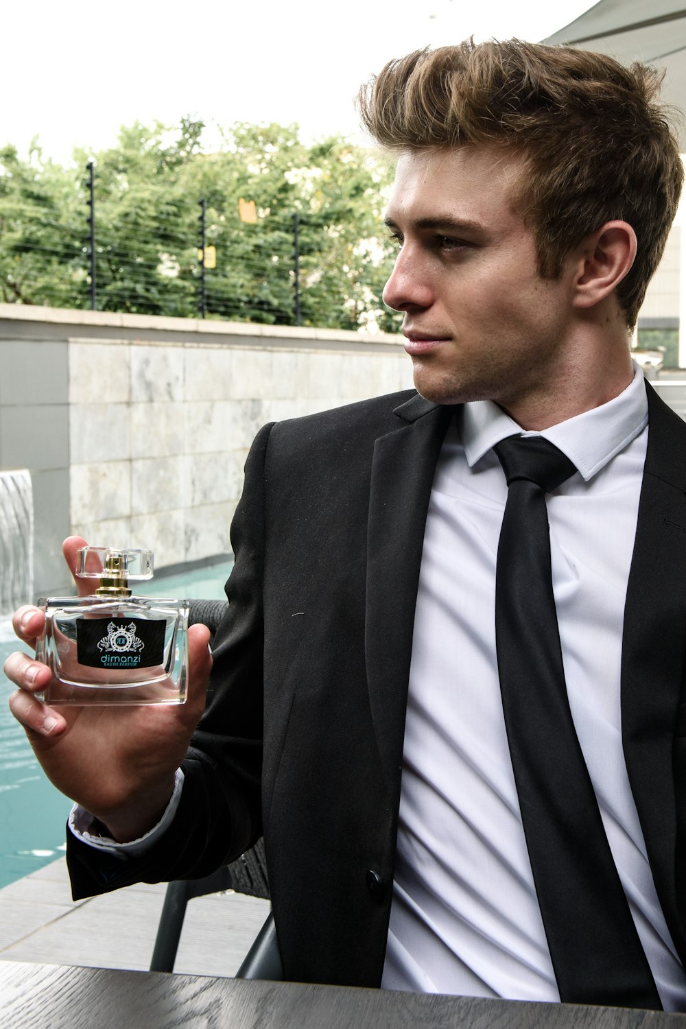 man in black suit holding red cup