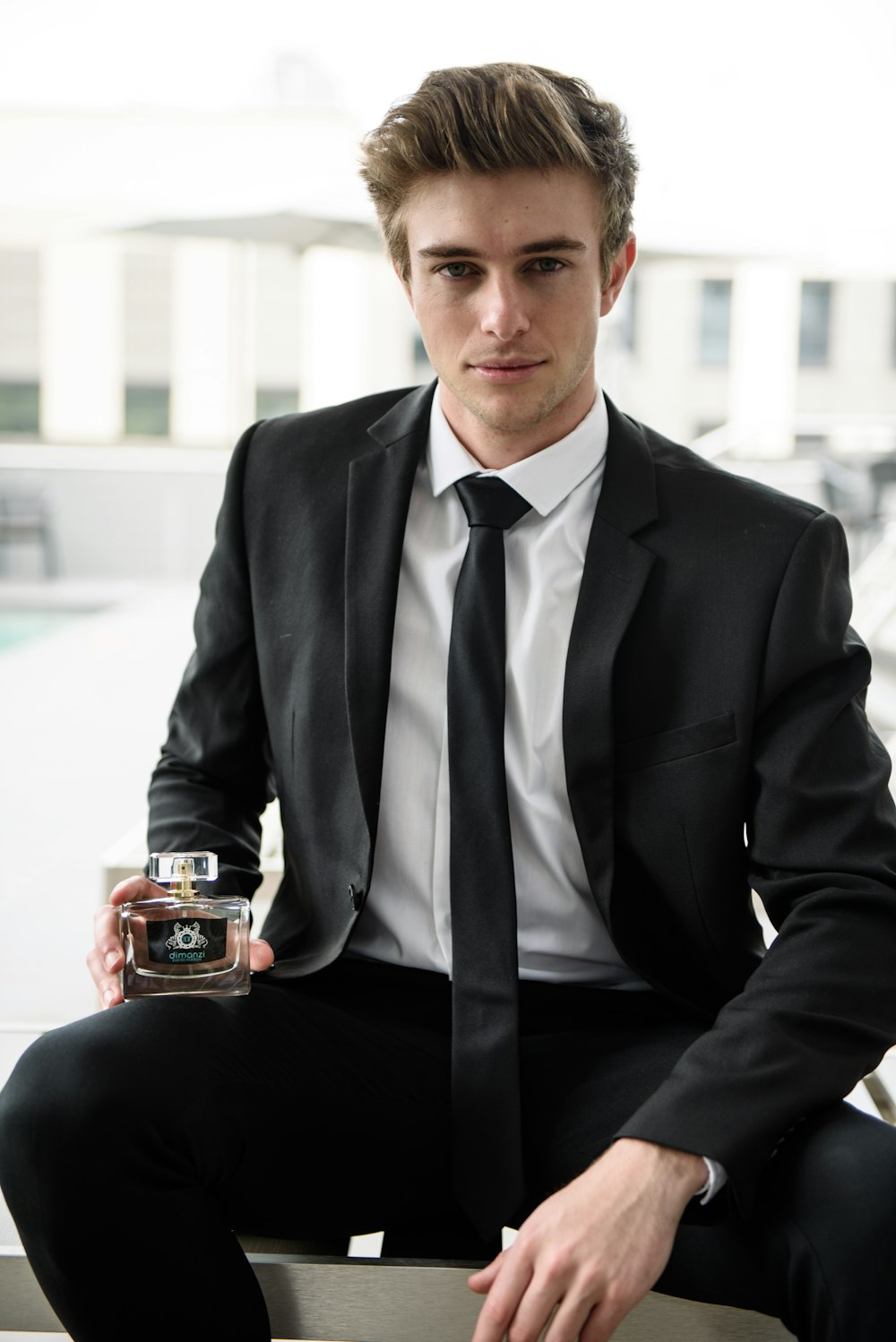 man in black suit holding brown ceramic mug