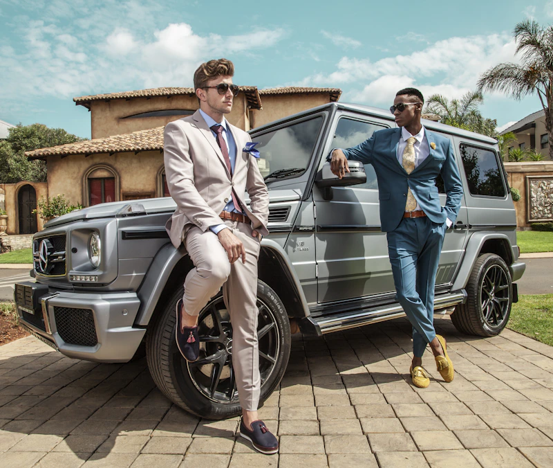 man in a blazer standing beside a luxury SUV