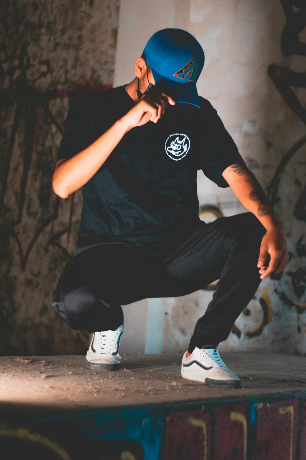 man in black t-shirt and black pants sitting on brown wooden seat