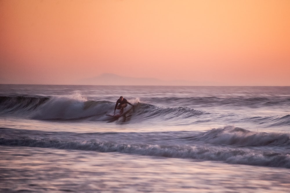 Persona surfeando sobre las olas del mar durante el día