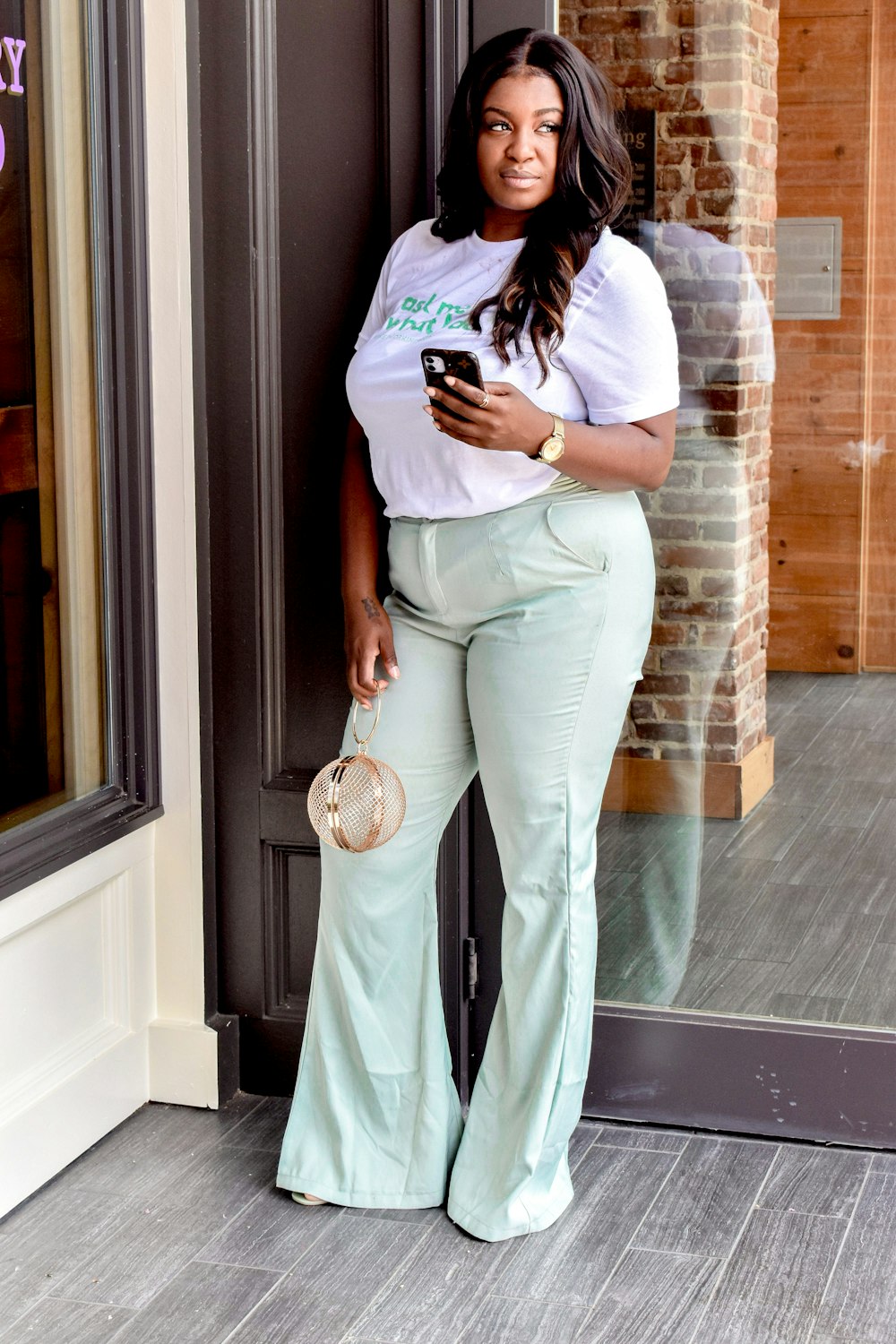 woman in white long sleeve shirt and gray pants standing beside glass window