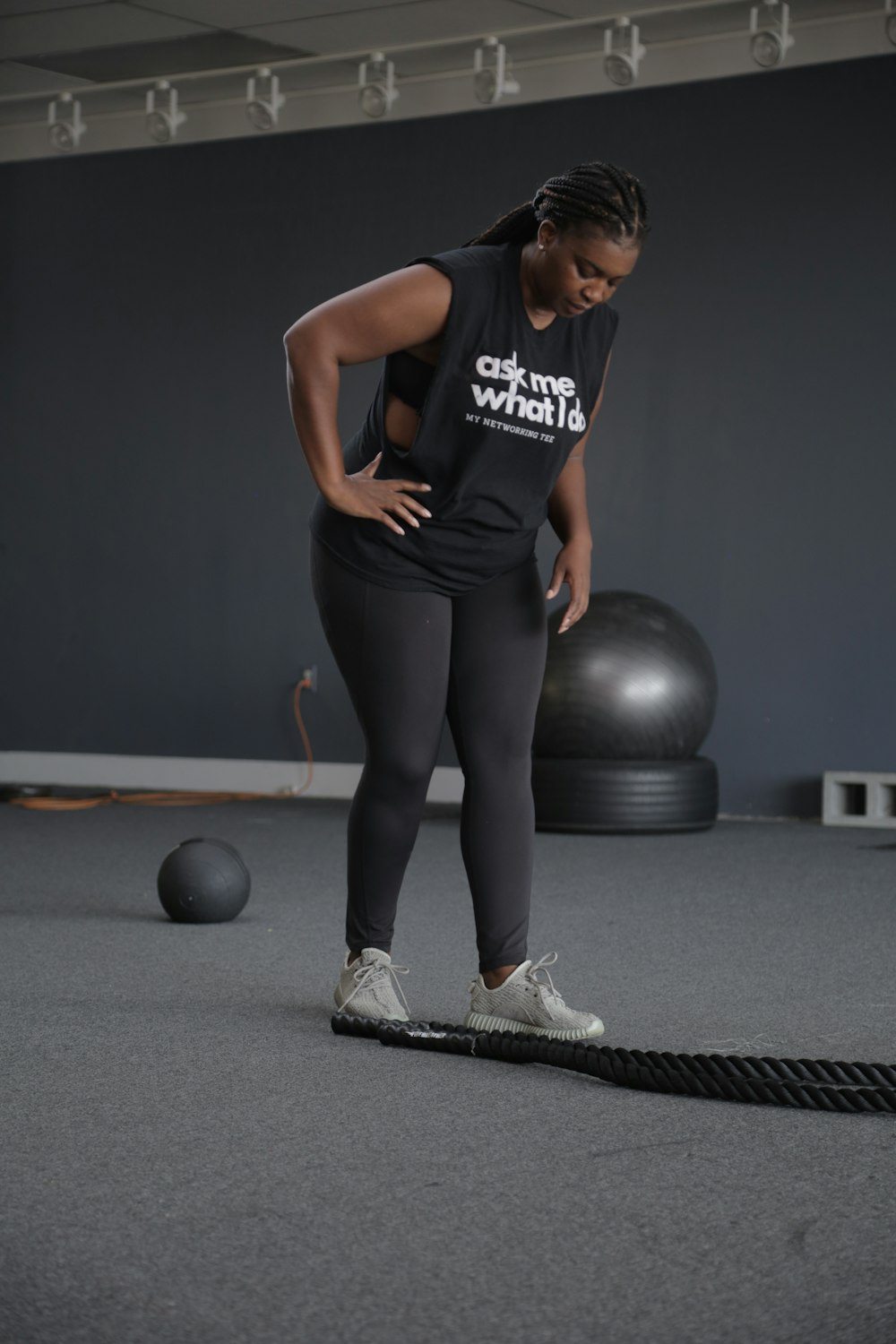 woman in black tank top and leggings holding black exercise ball