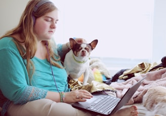 girl in blue jacket holding white and brown short coated puppy