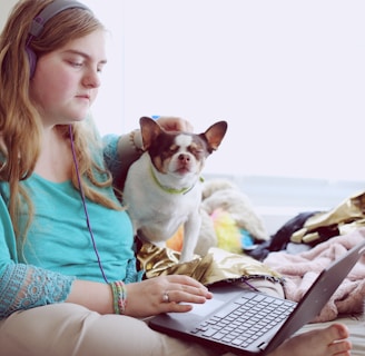 girl in blue jacket holding white and brown short coated puppy