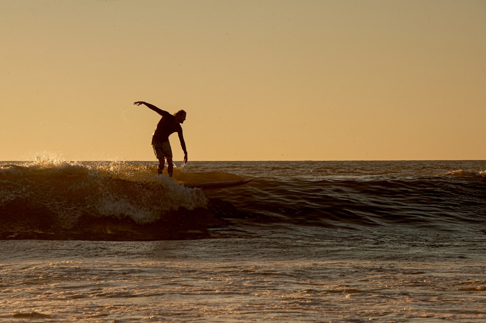 man in black shorts surfing on sea during daytime