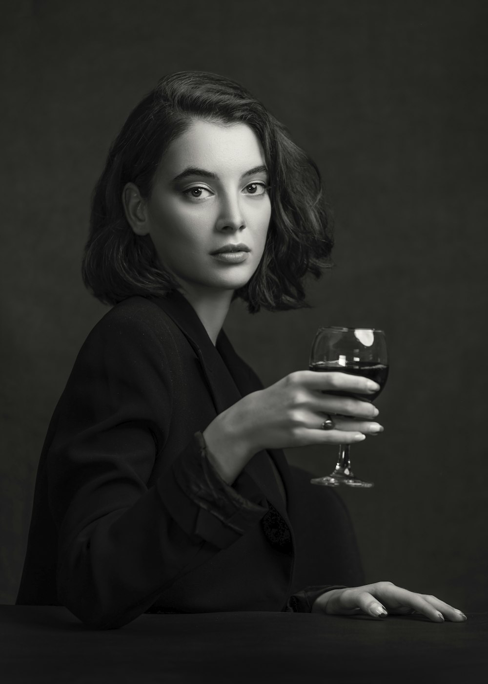 woman in black blazer holding clear drinking glass