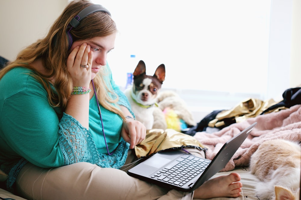 woman in teal long sleeve shirt holding black laptop computer