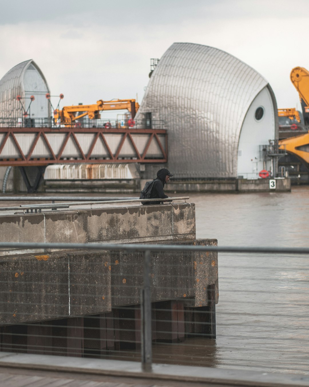 people walking on gray concrete bridge near white and gray building during daytime