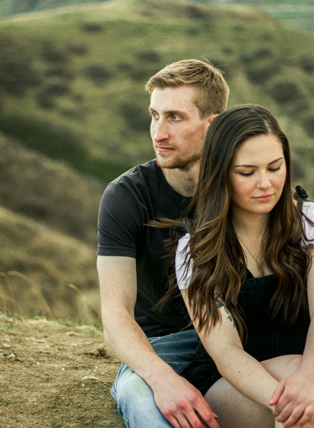 a man and a woman sitting on top of a hill