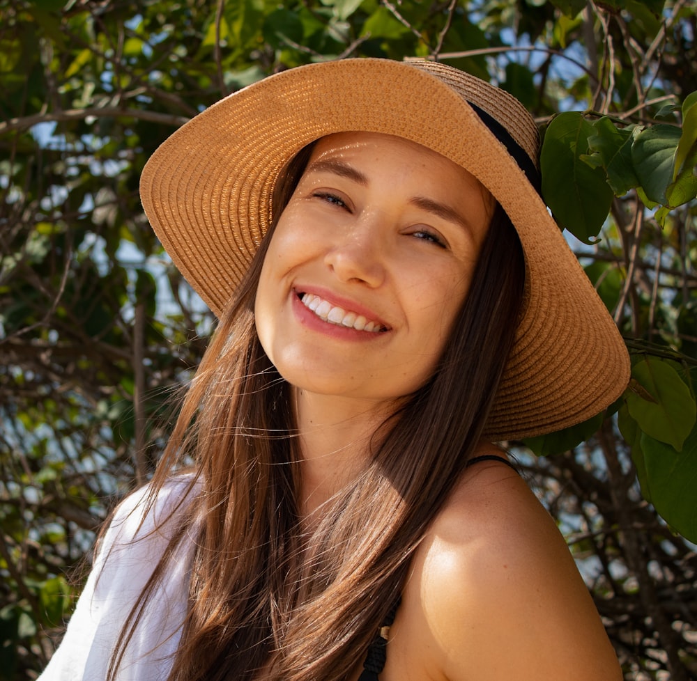 smiling woman wearing brown hat and white tank top