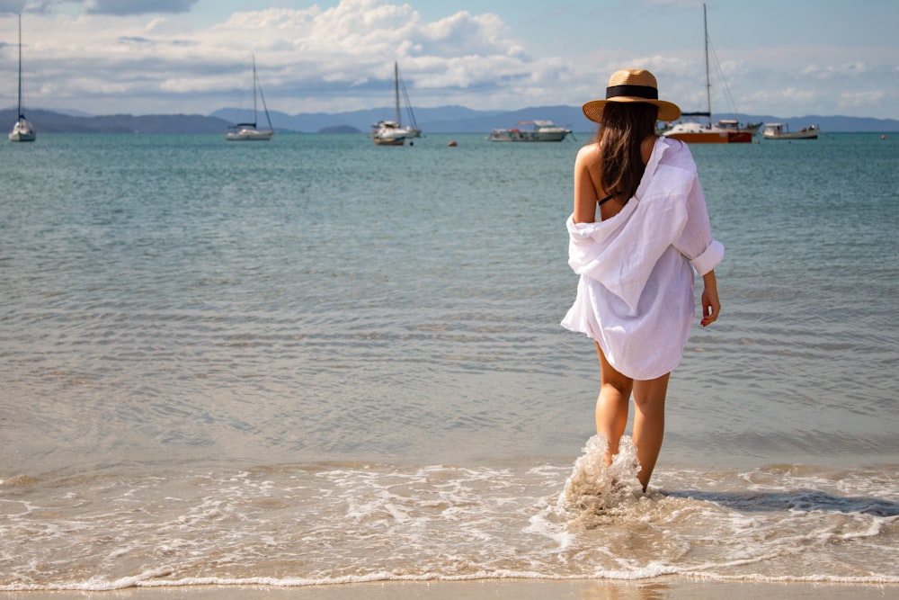 woman in white dress standing on beach during daytime