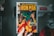 A person is holding a vintage comic book of 'The Invincible Iron Man'. The cover art features Iron Man in a dramatic scene with flames in the background and another character in a green outfit. The comic is enclosed in a protective plastic casing.
