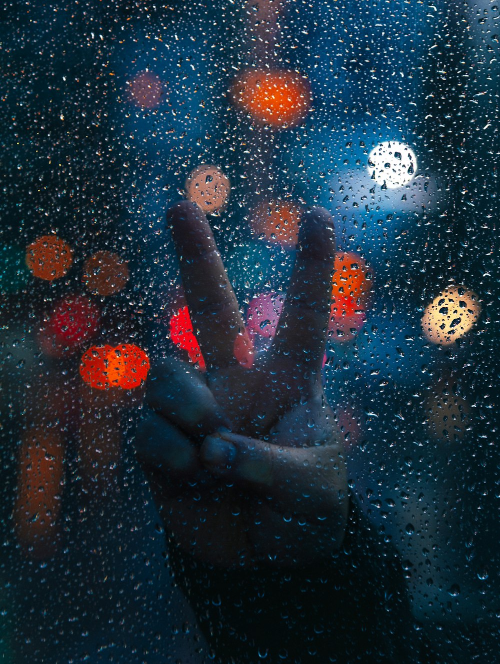 persons hand on glass with water droplets