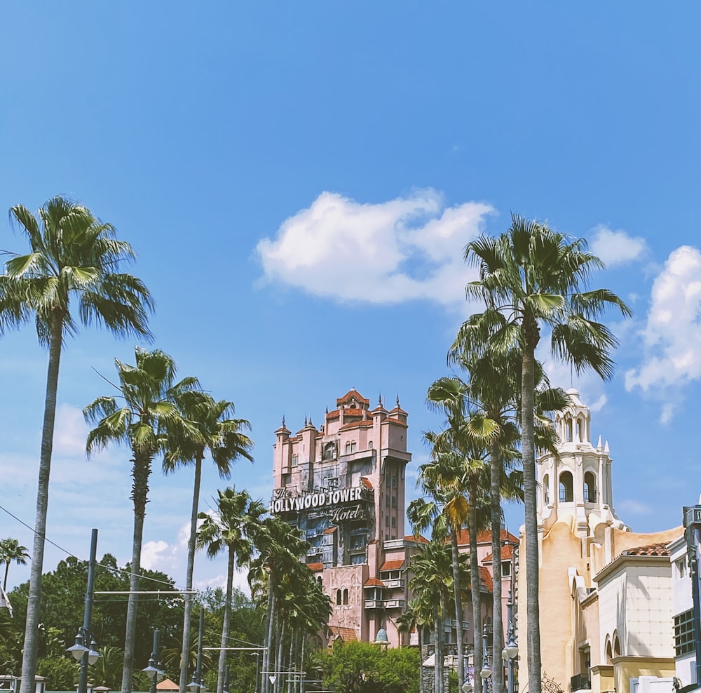 green palm trees near brown concrete building under blue sky during daytime