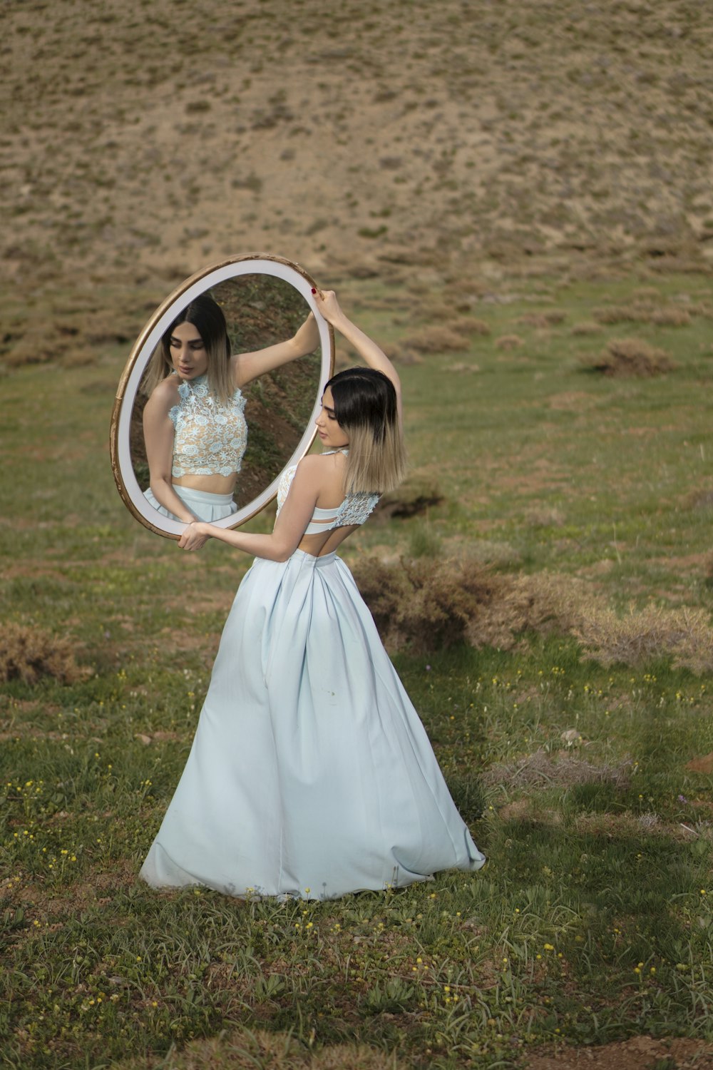 woman in white dress holding round mirror