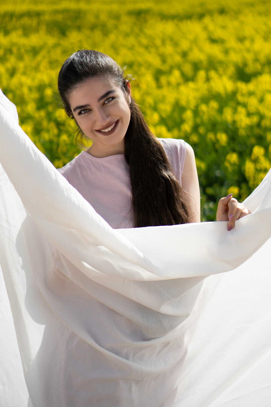 smiling woman in white dress standing on yellow flower field during daytime