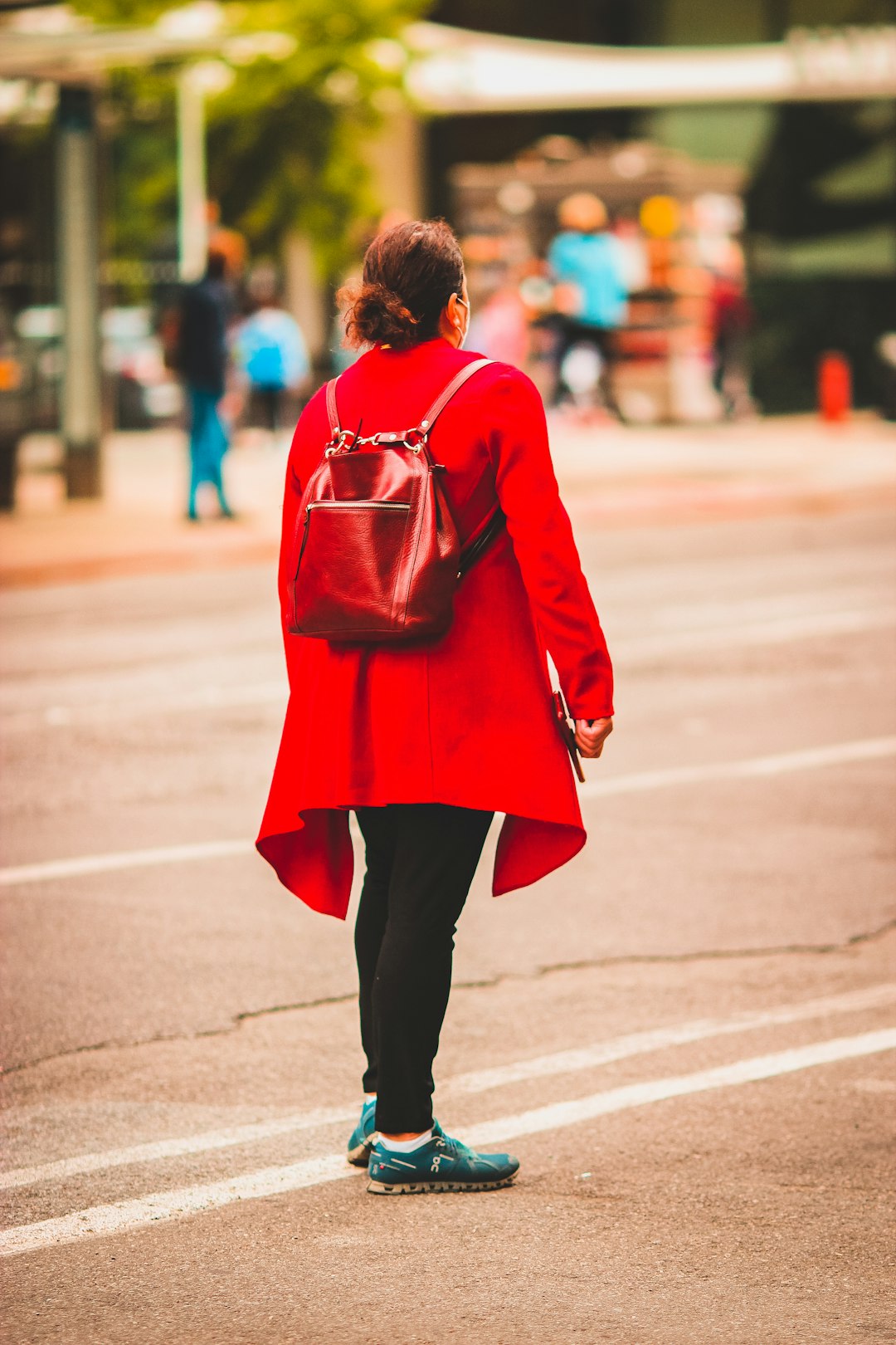 woman in red coat walking on street during daytime