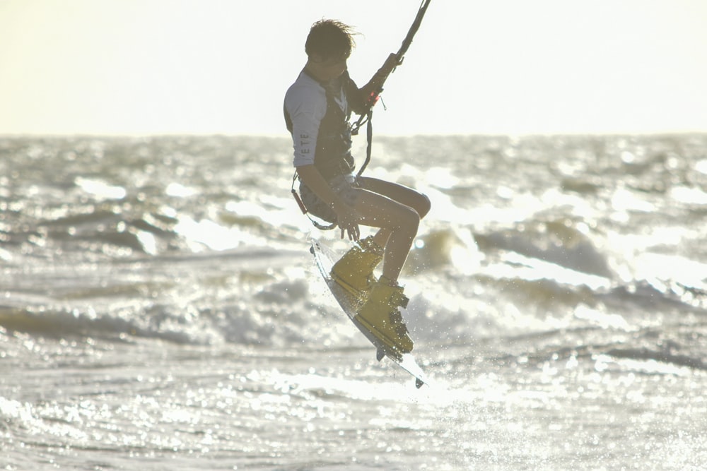 man in white long sleeve shirt and brown pants riding on black and white ski board