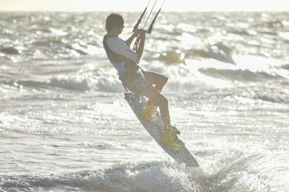 man in white shirt and brown shorts riding on white surfboard on beach during daytime