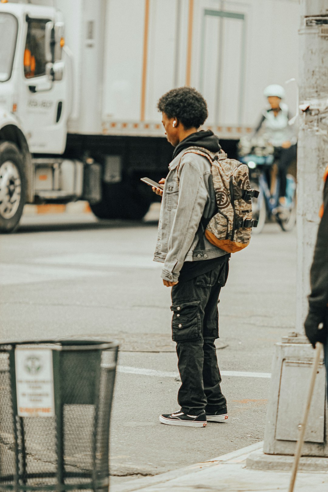 man in brown and black backpack standing on sidewalk during daytime