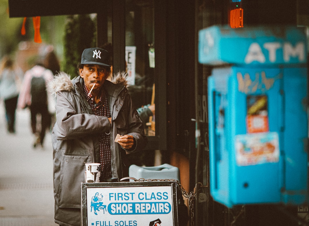 man in black jacket and black hat standing beside blue and white signage