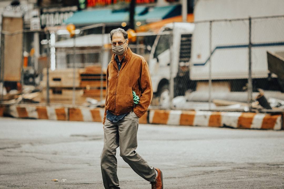 man in brown jacket and gray pants walking on street during daytime