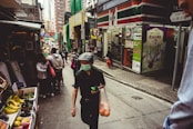 man in black tank top and white cap holding orange plastic bag