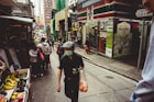 man in black tank top and white cap holding orange plastic bag