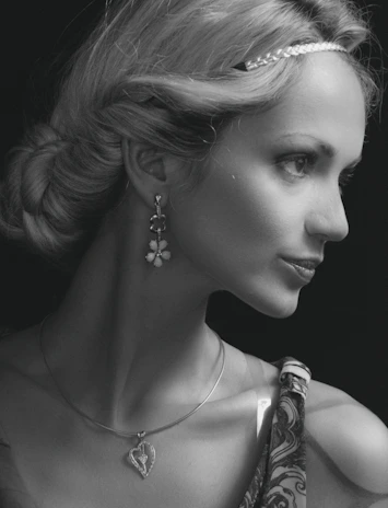 A stylish woman smiling while wearing a set of semi-jewels, highlighting earrings and a pendant.