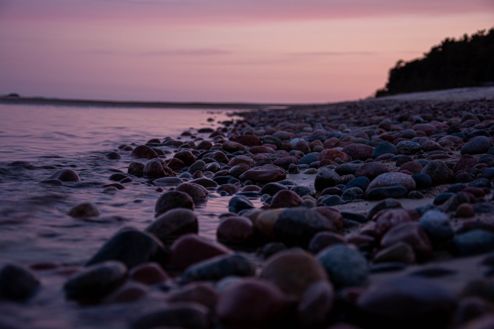 black and gray stones on seashore during sunset