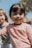 Smiling children wearing bright, stylish clothes playing outdoors on a sunny day.