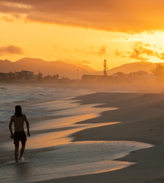 woman in black shirt walking on beach during sunset