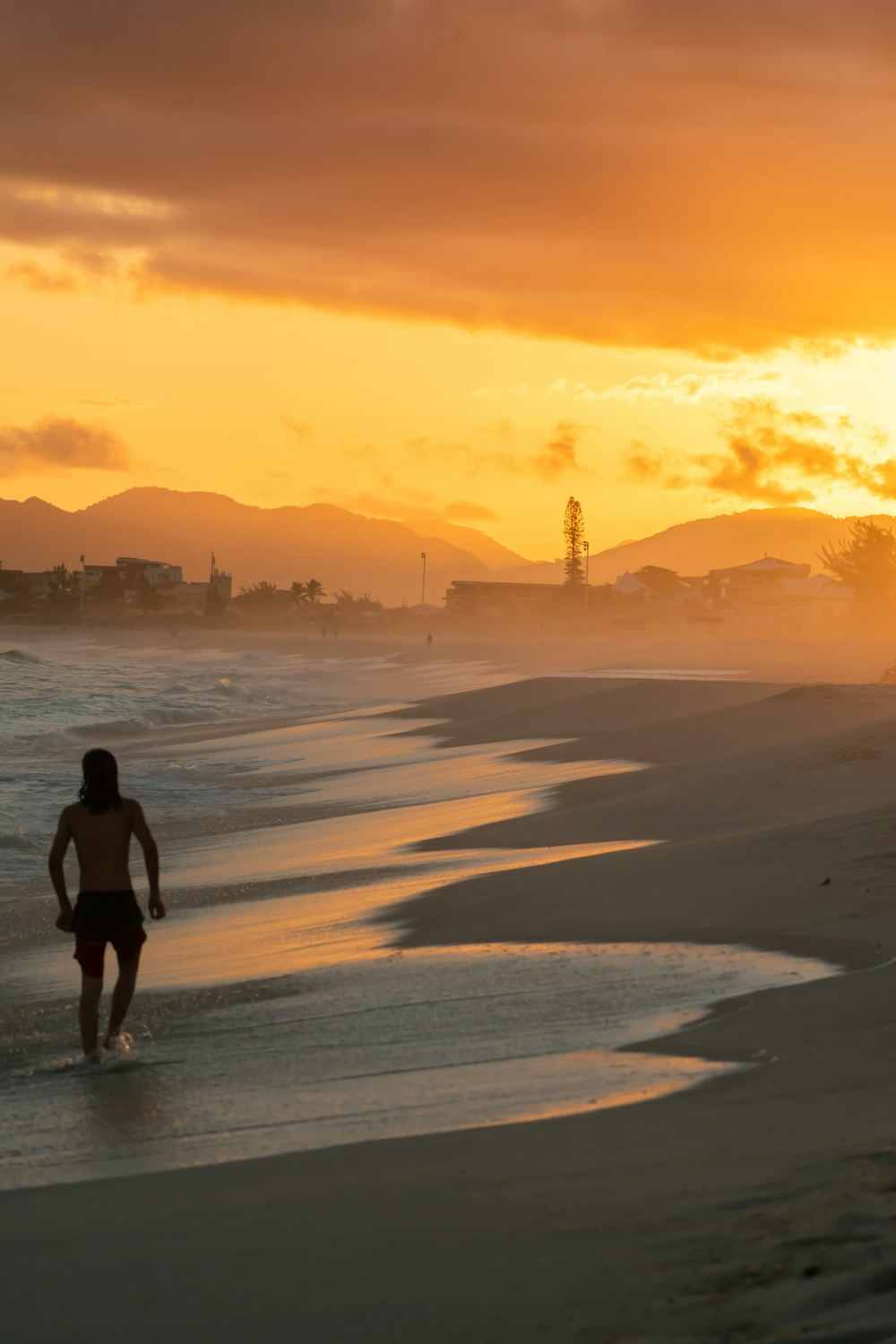 woman in black shirt walking on beach during sunset