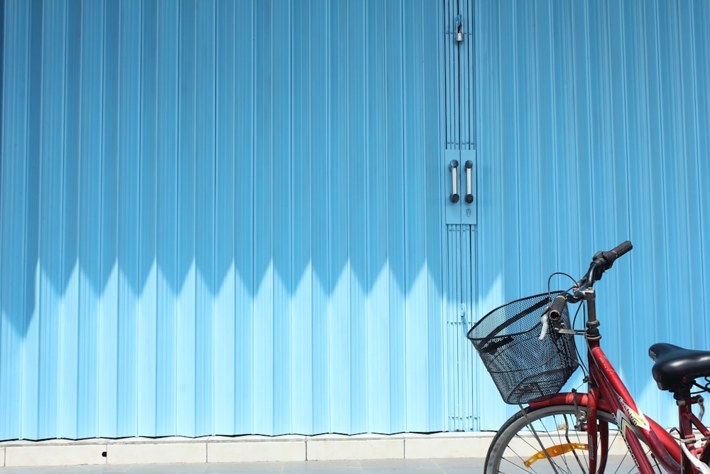 black city bike parked beside blue and white wall