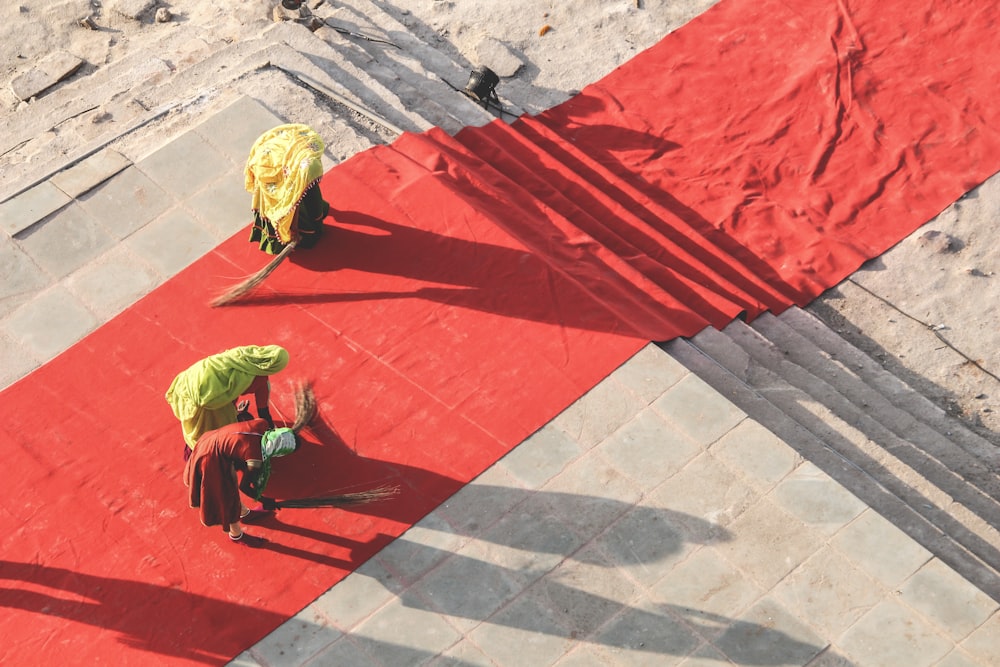 녹색 셔츠와 검은 바지를 입은 남자가 낮에 빨간 콘크리트 바닥을 걷고 있다