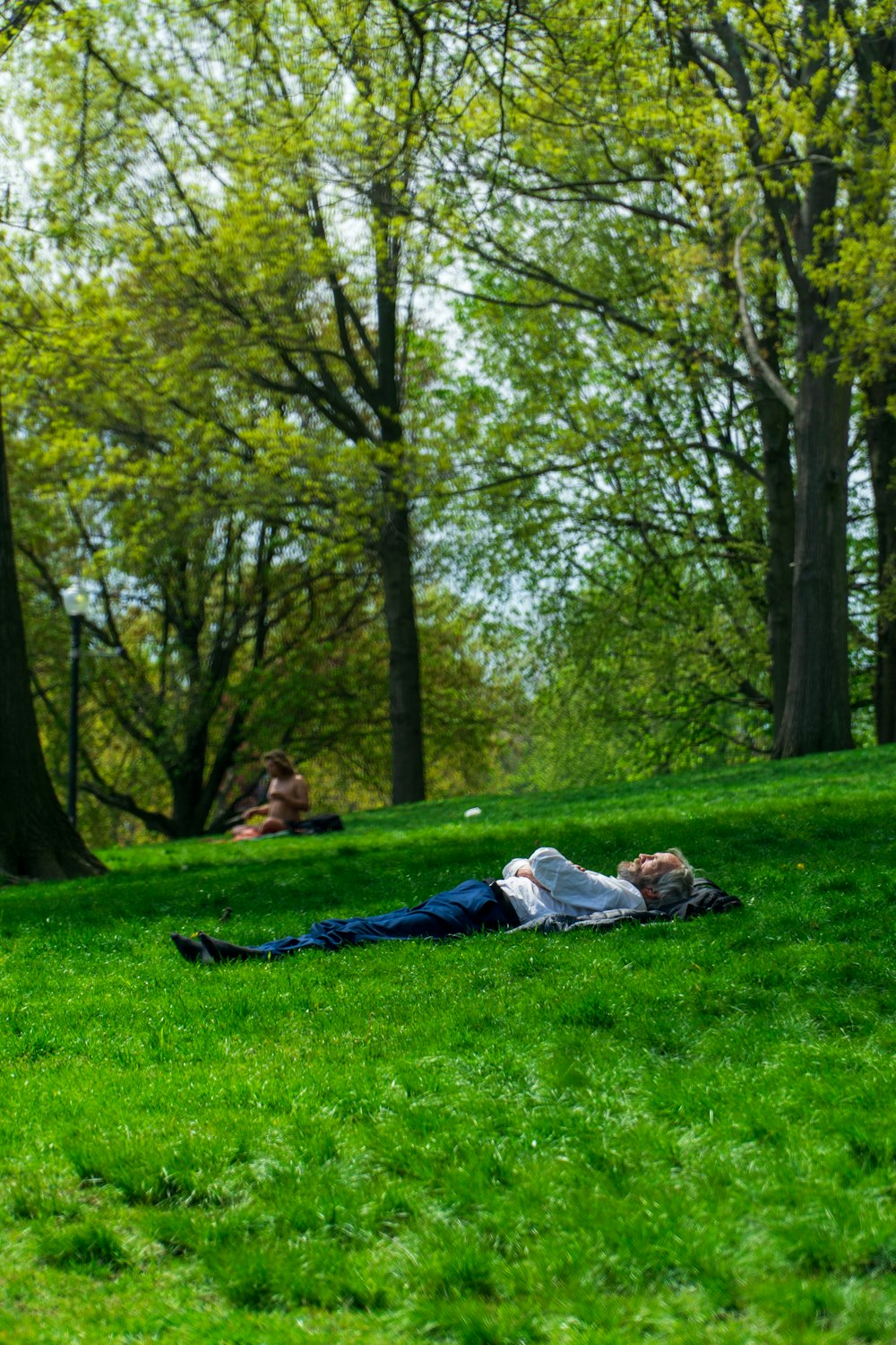 woman in white shirt lying on green grass field during daytime