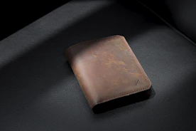 brown leather bifold wallet on black leather textile